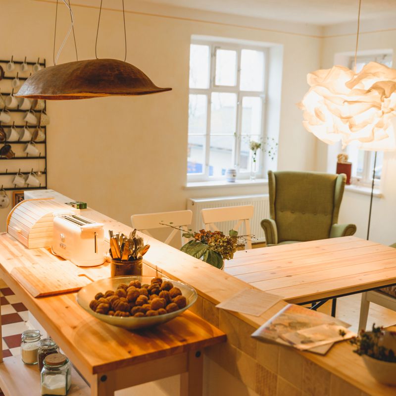 Helle Wohnküche mit Holzesstisch und vier weißen Stühlen