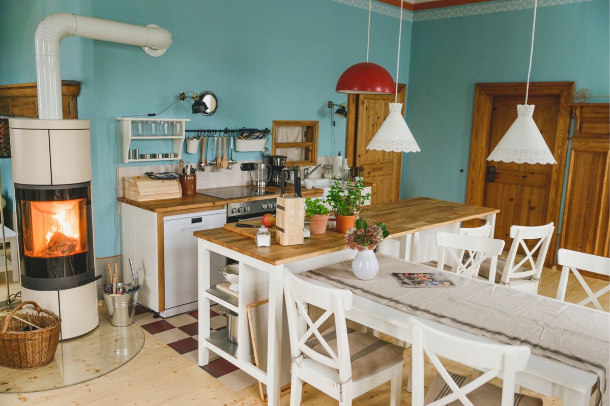 blau gestrichene Wohnküche mit Kamin, Esstisch und Stühlen