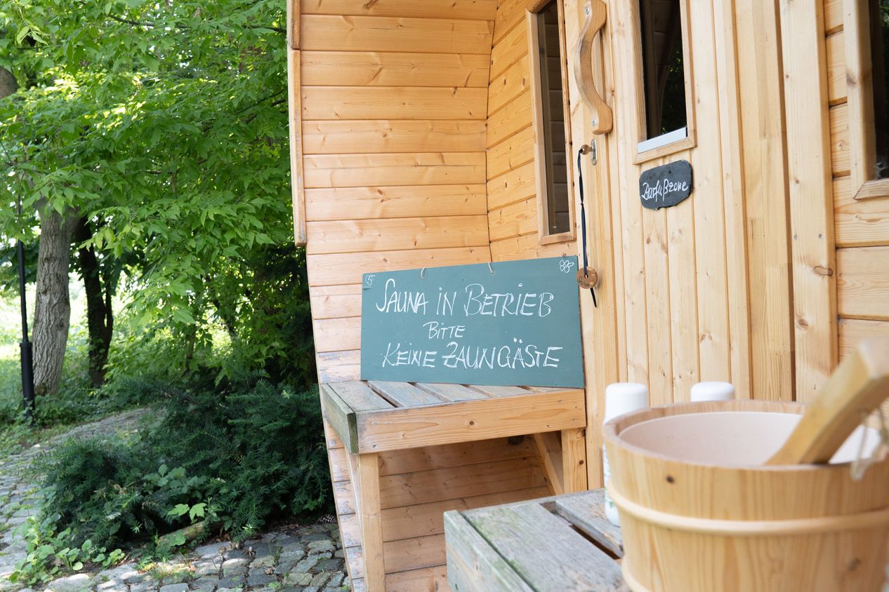 Detailaufnahme Sauna: Eingangsbereich Sauna und Schild mit Aufschrift "Sauna in Betrieb, bitte keine Zaungäste"
