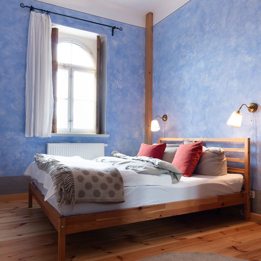 blau gestrichenes Schlafzimmer mit Doppelbett und Garderobe